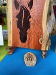 Wooden carvings featuring a horse's head design on a larger panel with a smaller decorative piece below.